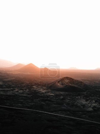Photo for Landscape vertical image - Volcanoes in Lanzarote on sunset. Moody and dark photo - panorama of black lava island Lanzarote. - Royalty Free Image