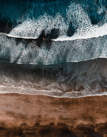 Photo for Top view by drone of yellow sand beach with ocean and waves. Beach with surfers on the beach at sunny day from above - vertical photo. - Royalty Free Image