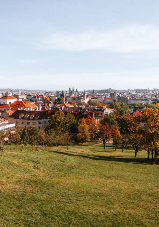 Photo for Beautiful park in Prague (Large Strahov garden) with colorful yellow-orange trees and amazing  view of city on background during the warm autumn day. - Royalty Free Image