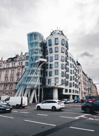 Photo for Vertical photo of Dancing house in Prague (Czech Republic) with traffic on crossroad on foreground and dramatic cloudy sky on background. Architectural concept - modern buildings in Europe. - Royalty Free Image