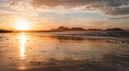 Photo for Panoramic view of beautiful golden hour on the Famara. Beach in Lanzarote - Canary Islands.  Photo of sunset on the beach with reflection of ocean and big waves in ocean and dramatic cloudy sky. - Royalty Free Image