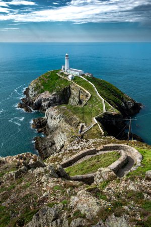 Téléchargez les photos : Sentier spectaculaire avec des étapes raides à l'île South Stack avec phare South Stack et vue sur la mer d'Irlande au nord du Pays de Galles, Royaume-Uni - en image libre de droit