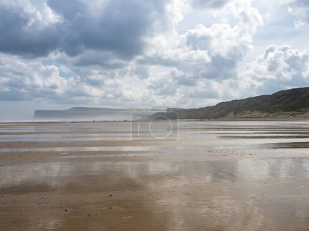 Storm clouds and reflections on Saltburn beach at low tide, North Yorkshire, England
