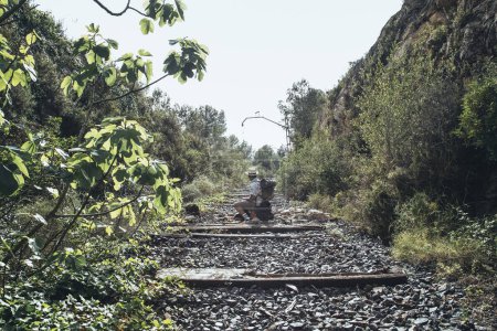 Téléchargez les photos : Voyageur avec un sac à dos au milieu des voies ferrées abandonnées - en image libre de droit