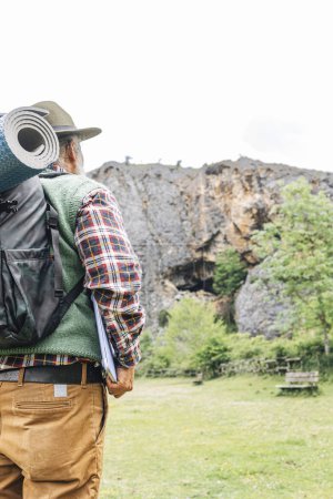 Téléchargez les photos : Voyageur indépendant avec tapis de sac à dos et ordinateur portable dans la nature, vue arrière. - en image libre de droit