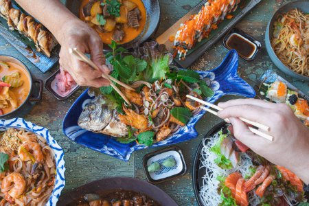 Téléchargez les photos : Mains avec baguettes manger thaï nourriture fermer, salades et wok, nourriture asiatique, vue sur le dessus. Cuisine japonaise et thaïlandaise. - en image libre de droit