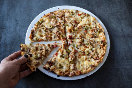 Téléchargez les photos : Les mains de l'homme tenant kebab pizza tranche sur la table du restaurant - en image libre de droit