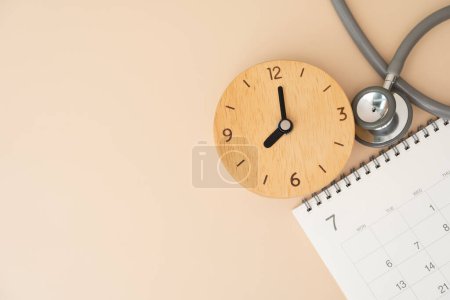 Vista superior del estetoscopio, reloj despertador y calendario en el fondo marrón, horario para comprobar el concepto saludable