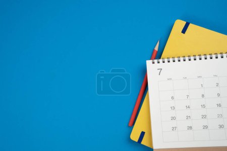 primer plano del calendario en el fondo de la mesa azul, planificación de reuniones de negocios o concepto de planificación de viajes