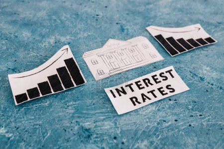Photo for Interest rates text with bank icon in between graphs with stats going up then going down, concept of economic struggles after the pandemic - Royalty Free Image