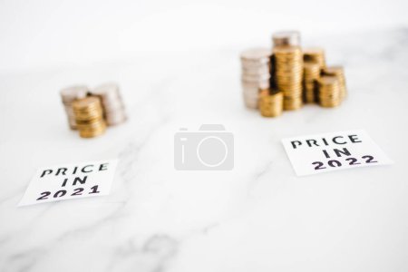 Photo for Inflation and cost of living going up concept, Price in 2021 vs Price in 2022 with small and big stacks of coins side by side for comparison - Royalty Free Image