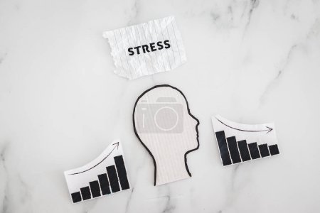 Photo for Mental health and mood swings conceptual image, cardboard head with Stress text on scrunched up torn paper with graphs showing stats going up and down - Royalty Free Image