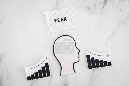 Photo for Mental health and mood swings conceptual image, cardboard head with Fear text on scrunched up torn paper with graphs showing stats going up and down - Royalty Free Image