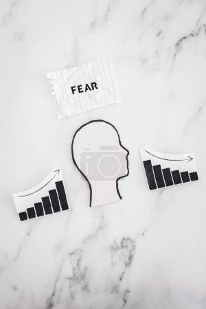 Photo for Mental health and mood swings conceptual image, cardboard head with Fear text on scrunched up torn paper with graphs showing stats going up and down - Royalty Free Image