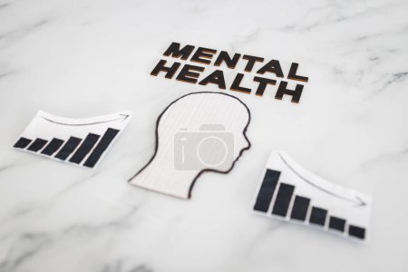 Foto de Mental health and mood swings conceptual image, cardboard head with Stress text on scrunched up torn paper with graphs showing stats going up and down - Imagen libre de derechos