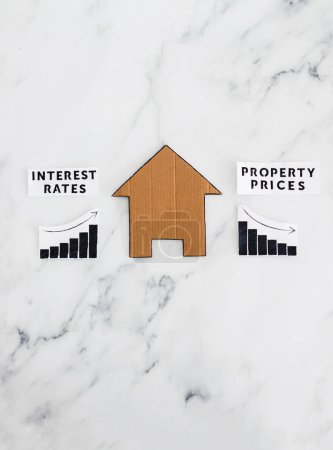 graphs with interest rates going up and property prices going down next to cardboard house, concept of post pandemic economy and inflation in winter 2022