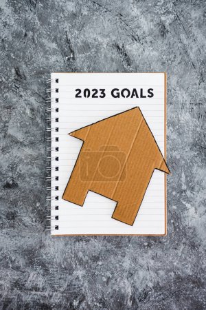 Téléchargez les photos : Concept of buying a house or settling down, 2023 goals on notebook with cardboard house - en image libre de droit