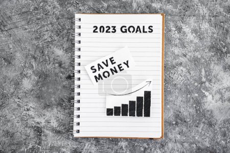Téléchargez les photos : Save money text with graph showing stats going up on 2023 goals notebook, concept of financial stability and being free from debt - en image libre de droit