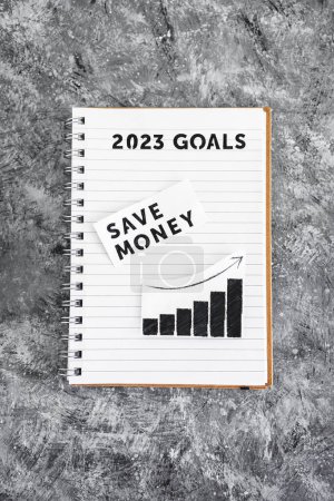 Téléchargez les photos : Save money text with graph showing stats going up on 2023 goals notebook, concept of financial stability and being free from debt - en image libre de droit