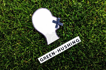 Foto de Green-hushing concept about companies staying silent about their environmental footprints and policies, text and face with  mouth shut on green grass - Imagen libre de derechos