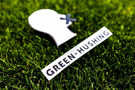 Photo for Green-hushing concept about companies staying silent about their environmental footprints and policies, text and face with  mouth shut on green grass - Royalty Free Image