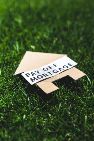 Photo for Financial independence and being free from debt, Pay Off Mortgage text over cardboard house on perfect green lawn shot under strong sunshine - Royalty Free Image