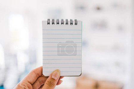 Photo for Hand holding notepad with blank copy space in front of stylish living room background, space for your text - Royalty Free Image