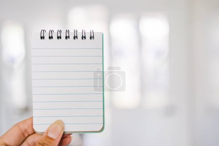 Photo for Hand holding small notepad with blank copy space in front of stylish entry door background, space for your text - Royalty Free Image