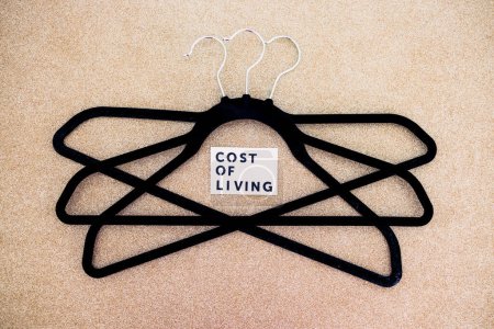 Photo for Shopping and purchasing power in the post pandemic economy, group of clothes hangers with Cost of Living text in the middle concept of buyers reducing their spending - Royalty Free Image