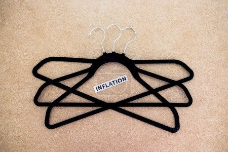 Photo for Shopping and purchasing power in the post pandemic economy, group of clothes hangers with Inflation text in the middle concept of buyers reducing their spending - Royalty Free Image