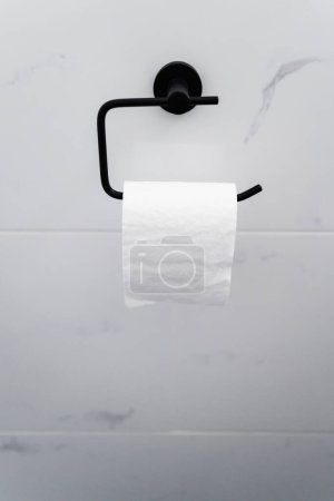 titular de rollo de papel higiénico negro en pared de baldosas de mármol blanco, renovación del hogar y detalle de diseño interior en tocador o baño