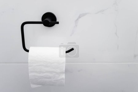 titular de rollo de papel higiénico negro en pared de baldosas de mármol blanco, renovación del hogar y detalle de diseño interior en tocador o baño