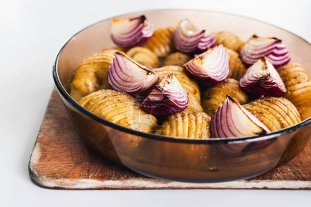 Foto de Patatas hasselback asadas a base de plantas con cebolla en bandeja redonda, recetas de alimentos veganos saludables - Imagen libre de derechos