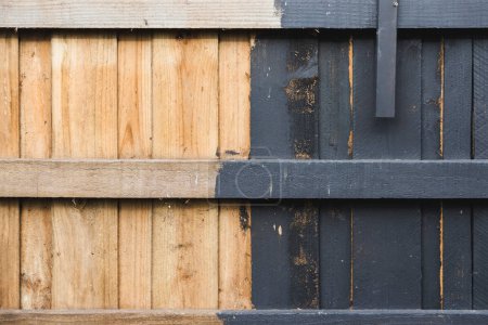Halb bemalte Hinterhof-Stützmauer oder -Zaun, Holzkohle gegen nacktes Holz, Heimwerker und Sanierungskonzept