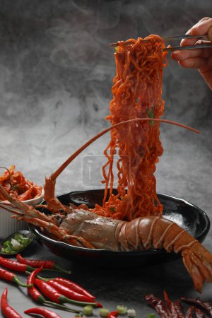 Foto de Fideos instantáneos secos picantes coreanos con langosta espinosa pintada y kimchi sobre fondo negro. Concepto de alimentos asiáticos. - Imagen libre de derechos