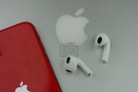 Photo for Bangkok, Thailand - November 15, 2022 : Apple AirPods 3 next to iPhone 11 product red model placed on MacBook pro. White Apple AirPods 3 with spatial audio - Royalty Free Image