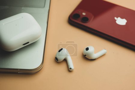 Photo for Bangkok, Thailand - November 19, 2022 : Apple AirPods (3rd generation) with wireless charging case and next to red Iphone 11 - Royalty Free Image