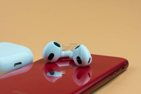 Photo for Bangkok, Thailand - December 10, 2022 : Closeup of new wireless headphones apple AirPods 3 and red iPhone 11 - Royalty Free Image