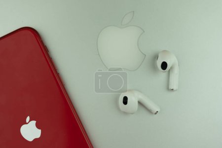 Photo for Bangkok, Thailand - December 17, 2022 : Apple AirPods 3 next to iPhone 11 product red model placed on MacBook pro. White Apple AirPods 3 with spatial audio - Royalty Free Image