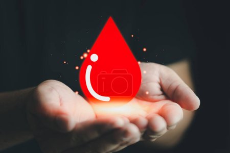 Téléchargez les photos : Icône coeur rouge dans les mains de l'homme. Concept de don de sang. Journée mondiale des donneurs de sang - en image libre de droit
