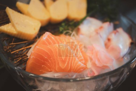 Foto de Salmón Sashimi y huevos de tamago dulce sushi sobre hielo en el tazón de cristal. Estilo de comida japonesa - Imagen libre de derechos
