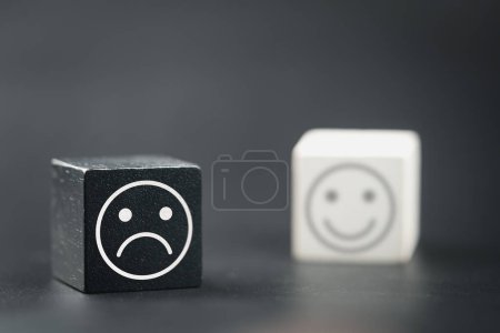 Téléchargez les photos : Cube en bois avec un visage malheureux, bloc de bois avec un visage de stress émotionnel et des pensées confuses, dépression et inquiétude pour la détresse et le visage sourire en bloc de bois blanc de fond flou - en image libre de droit