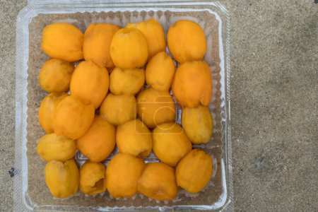 Foto de Peel of fresh maprang, is a popular tropical fruit in Thailand, fresh yellow-orange flesh is peeled in a plastic box. Characteristics of oval-like eggs - Imagen libre de derechos