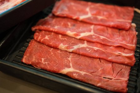 Photo for Fresh beef raw sliced with marbled texture served on black tray for Sukiyaki and Shabu - Royalty Free Image