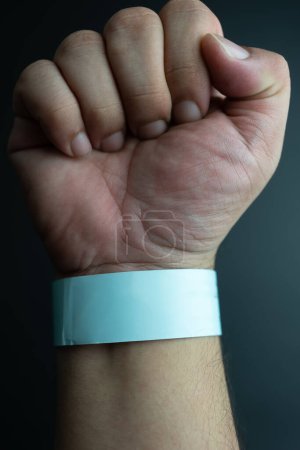 Photo for Blue paper wristband mockup on persons arm. Empty adhesive bangle wristlet sticker on male hand, blue paper bracelet, check tape, event ticket concept - Royalty Free Image