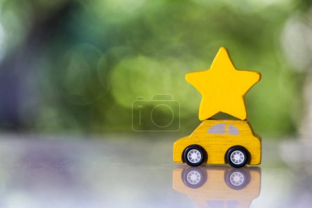Holzgelbes Spielzeugauto trägt vor Naturkulisse einen leuchtenden Stern auf dem Dach, die Scoring-Zufriedenheitsumfragen