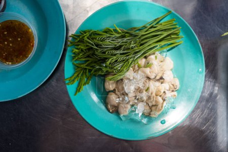 Téléchargez les photos : Huître crue et fraîche servie avec des feuilles d'acacia. Cuisine thaïlandaise menu populaire de fruits de mer. - en image libre de droit