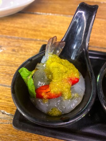 Téléchargez les photos : Crevettes crues trempées dans de la sauce de poisson servie sur un mini bol - en image libre de droit