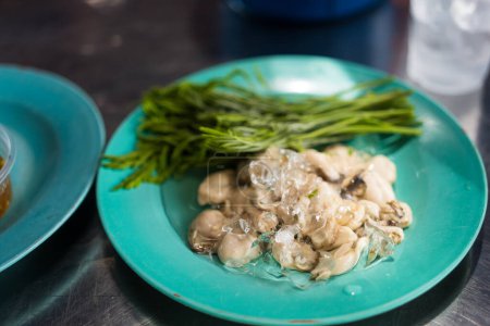 Téléchargez les photos : Huître crue et fraîche servie avec des légumes acacia pour manger sur un plat vert. - en image libre de droit