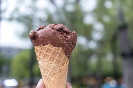 Téléchargez les photos : Une main masculine tenant un chocolat glacé dans un cône de gaufre. Vacances et plaisir, se détendre et profiter - en image libre de droit